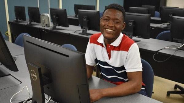 smiling male student sitting at a computer desk